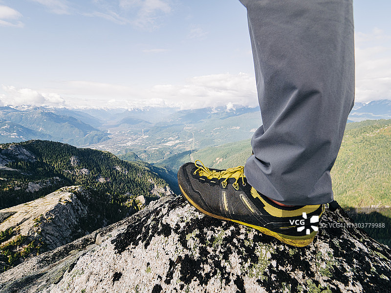 跑步鞋的观点，站在山顶俯瞰一个森林深谷图片素材