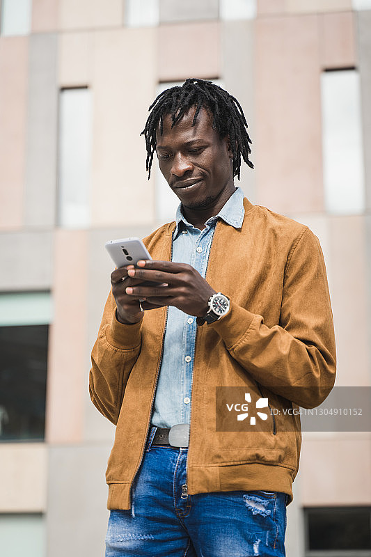 自信的非洲黑人在现代城市的商业区使用智能手机图片素材