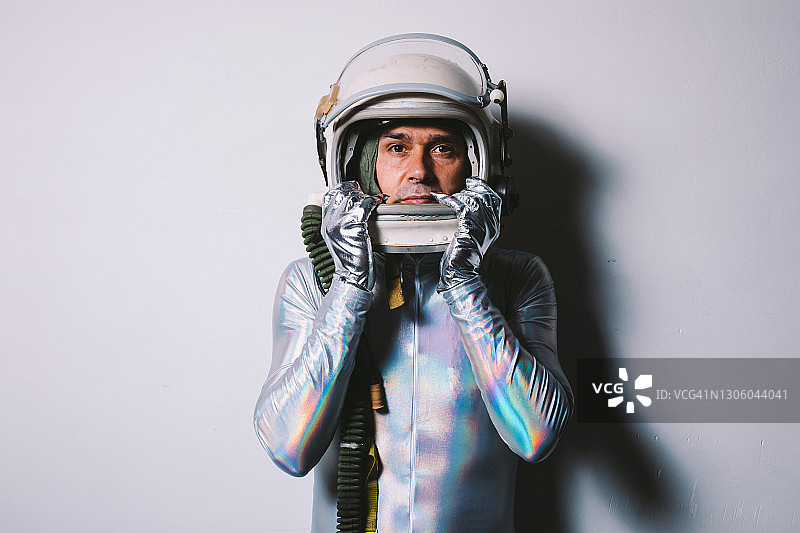 穿着银色紧身衣戴着复古宇航员头盔的男人，直视前方图片素材