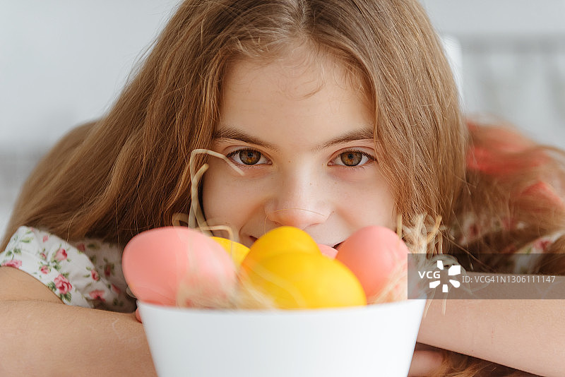 一个白色可爱的10岁欧洲女孩与黄色和粉红色的复活节彩蛋靠近图片素材