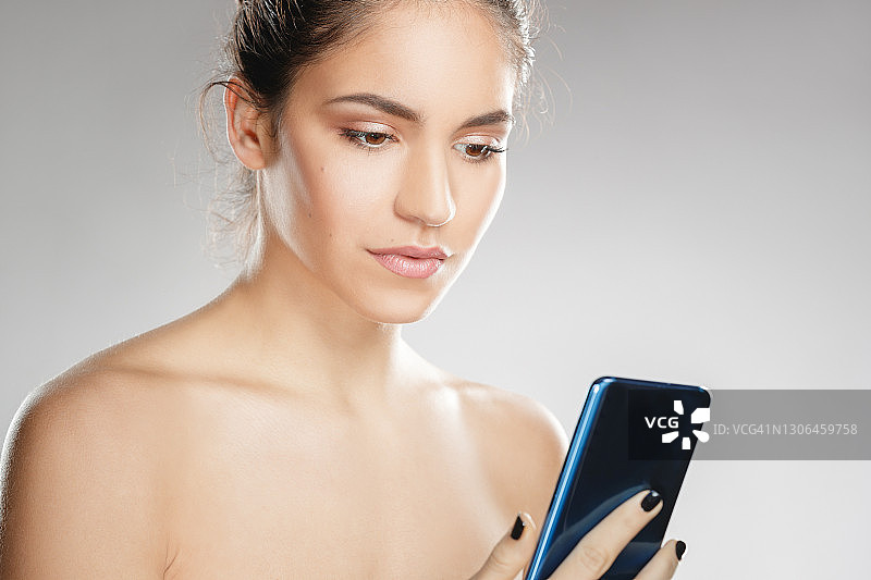 一个漂亮的年轻女子拿着手机的大头照图片素材