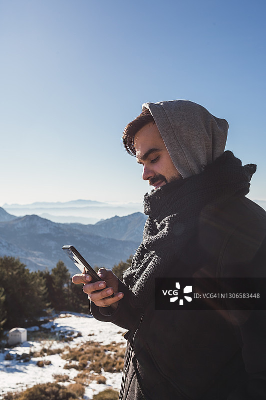 一个男人在雪地里用智能手机发信息的照片图片素材