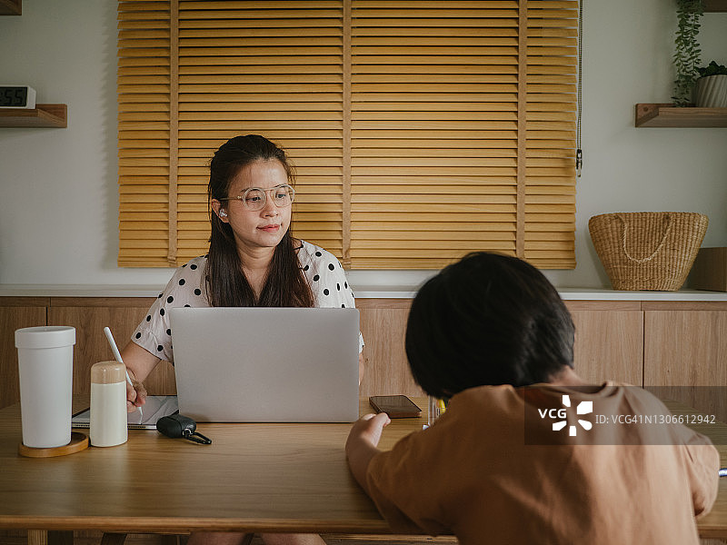 亚洲儿子在家和母亲一起参加网络课程。图片素材