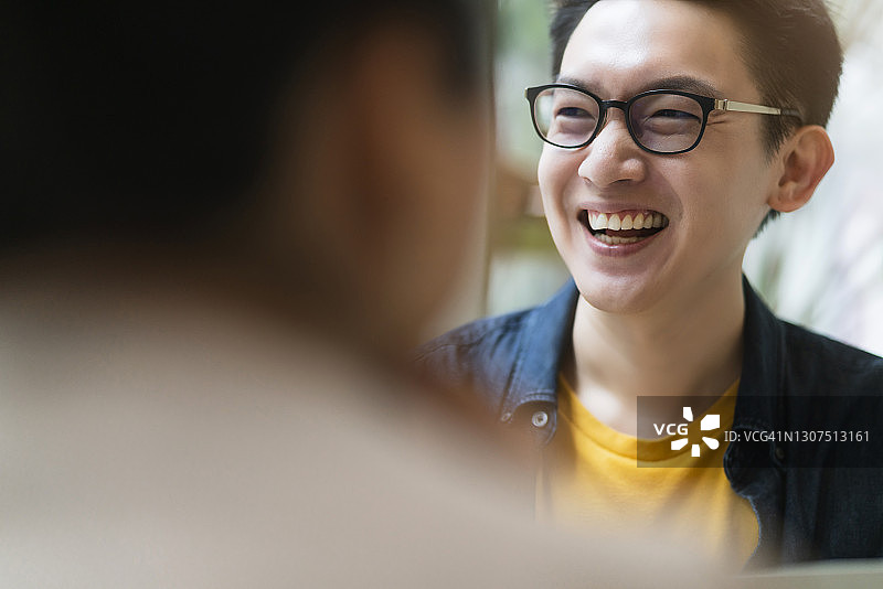 幸福微笑的亚洲男性休闲会议与他的伙伴在咖啡馆图片素材