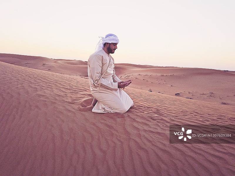 阿拉伯人在阿拉伯的沙丘上祈祷图片素材