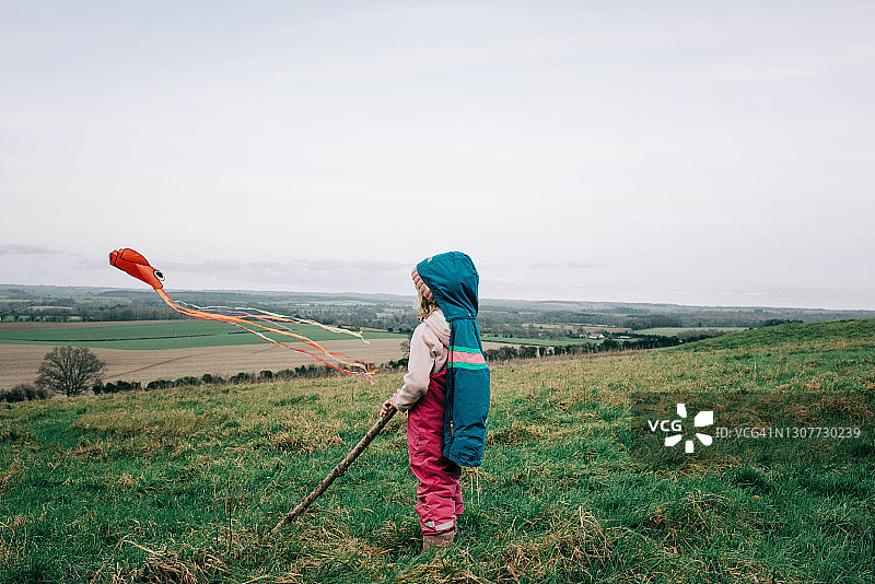 一个年轻女孩在冬天的英国乡村放风筝图片素材