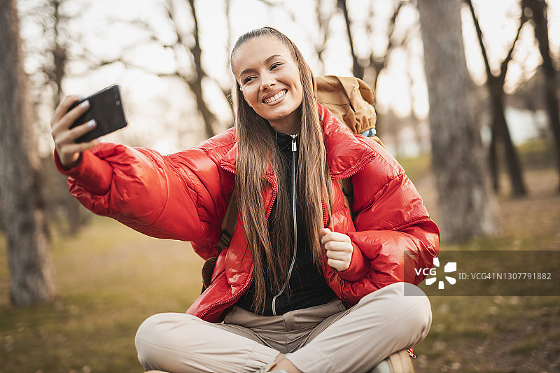 年轻的微笑的女人徒步在自然的山和连接一个移动电话图片素材