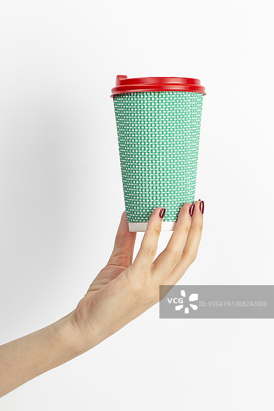 女性手握一次性咖啡杯绿色白色背景。图片素材