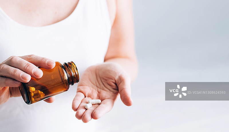 药片装在女性手上的瓶子里。健康与医学图片素材