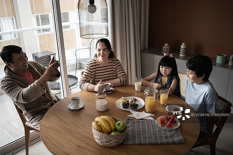 父亲在家拍摄孩子们吃早餐时的情景图片素材
