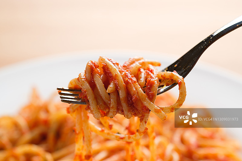 意大利面是包在叉子上的。在白色背景或桌子上，陶瓷盘子上放番茄酱意大利肉酱面。素食和素食食品的概念。食品的背景。特写镜头。图片素材
