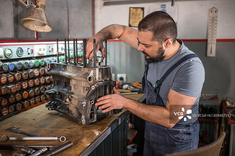 一个年轻人在汽车修理厂修汽车发动机图片素材