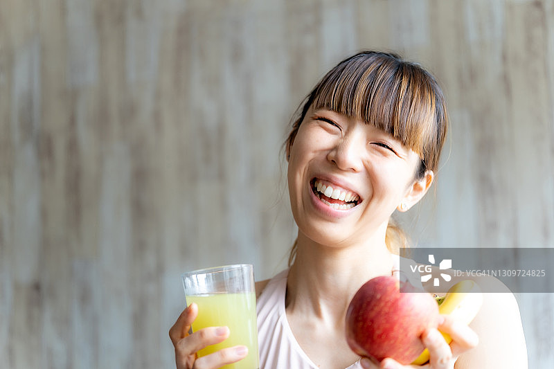 亚洲妇女拿着新鲜的果汁和微笑图片素材
