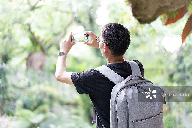 男人在森林里用智能手机拍照图片素材