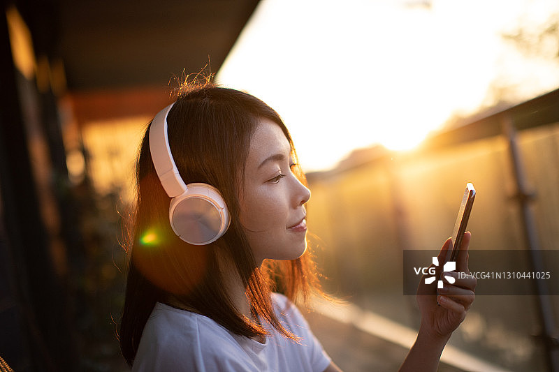 年轻女子用耳机和智能手机听音乐图片素材