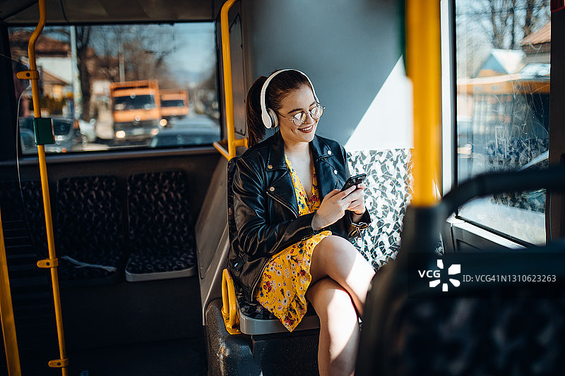 一名年轻女子在公交车上一边发短信一边听音乐图片素材