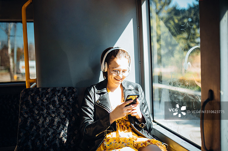 年轻女子在公交车上边笑边发短信，边听音乐图片素材