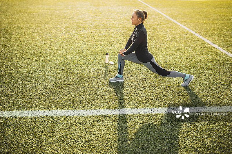 妇女伸展和热身跑步前在绿色的草地上的体育场图片素材