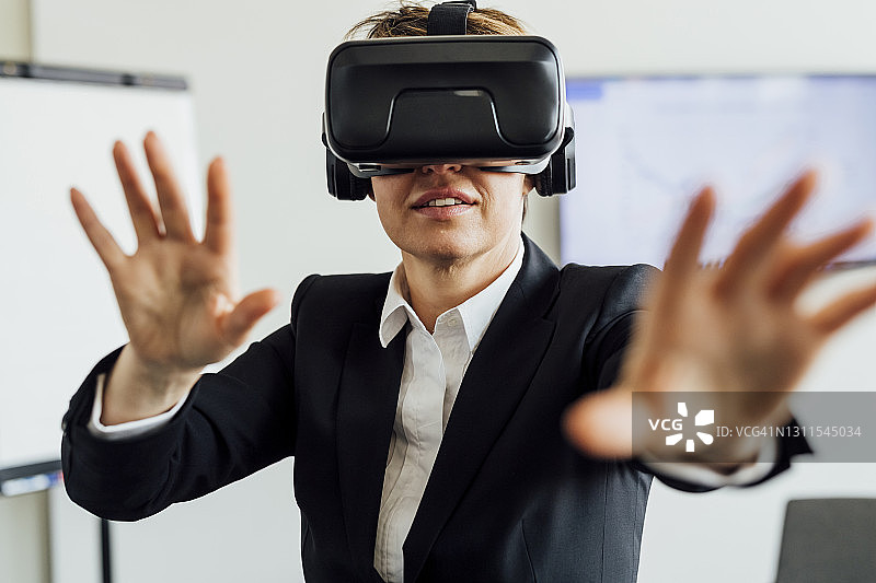 女商人戴着虚拟现实模拟器在办公室打手势图片素材