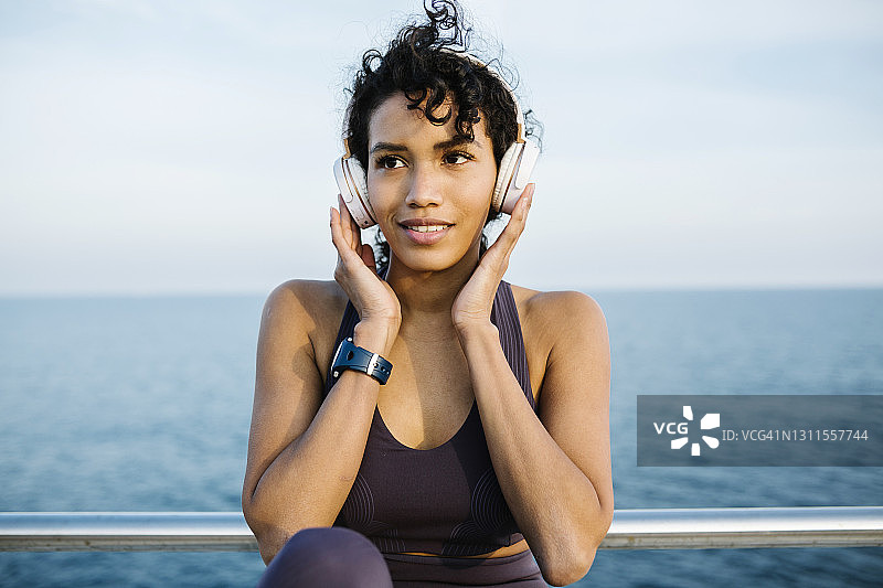 女运动员戴着耳机在大海前听音乐图片素材