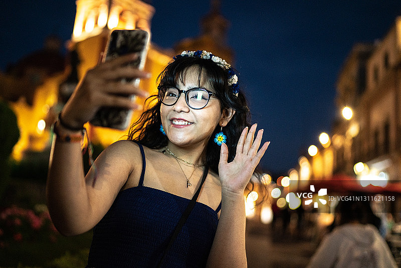 女孩在街上用智能手机视频通话时挥手图片素材