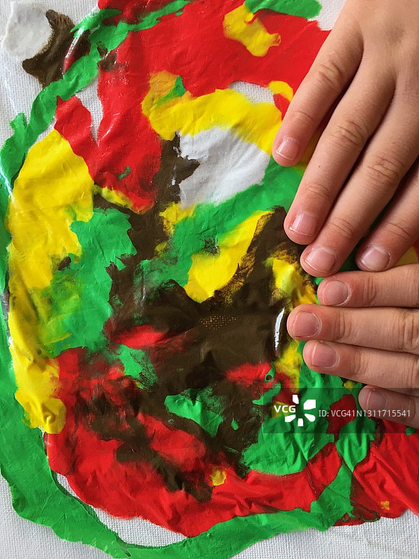 孩子的手通过帆布上的塑料袋移动颜料图片素材