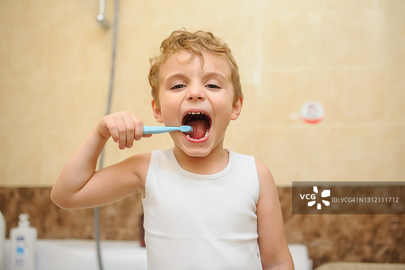 一个金发男孩在浴室里刷牙的照片图片素材