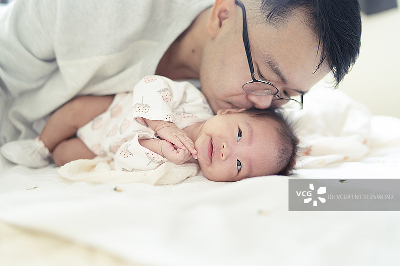 单身父亲亲吻自己的女儿，在家里洗完澡后给刚出生的女婴换衣服图片素材