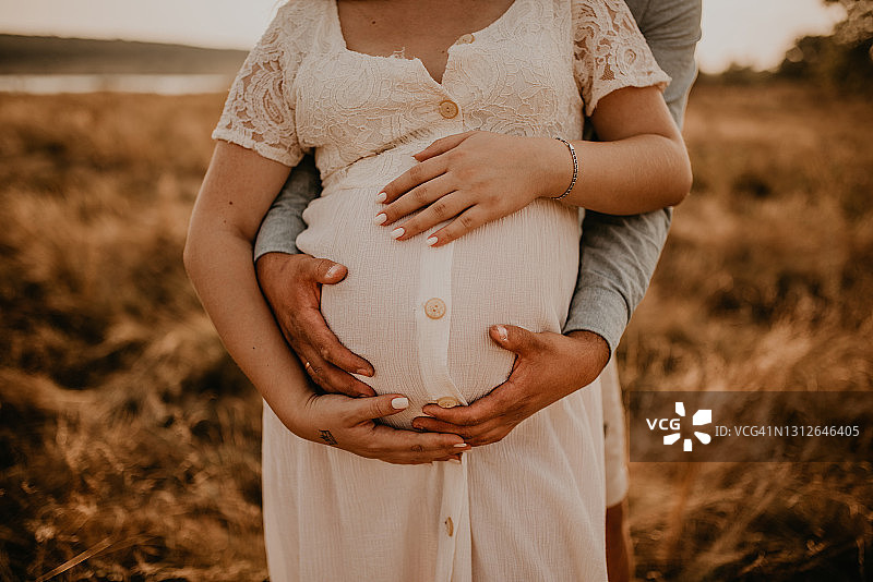 未来的妈妈和爸爸的手紧紧地抱着怀孕的大肚子图片素材