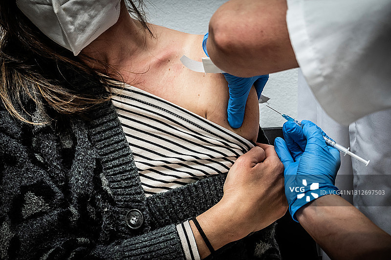 在西班牙马德里一家卫生中心接受COVID-19疫苗的妇女图片素材