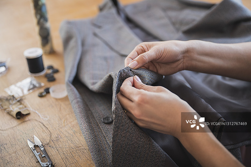 女裁缝完成在夹克上的手缝纽扣图片素材