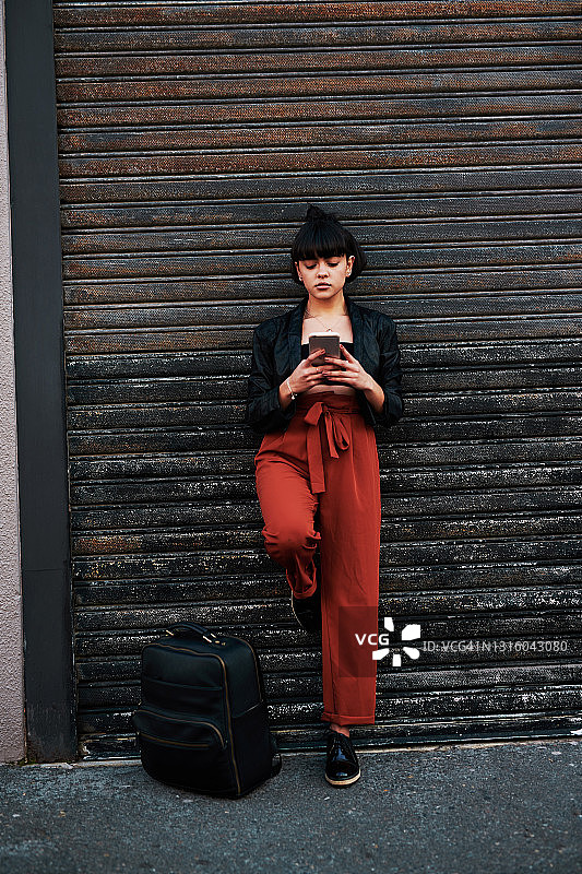 照片中，一名年轻女子站在车库门前使用手机图片素材