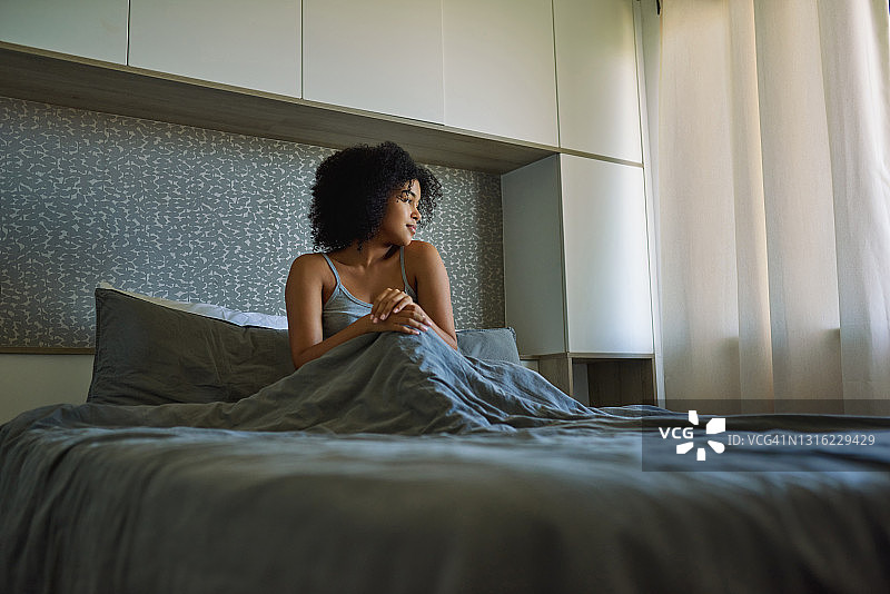 一名年轻女子醒来后坐在床上的照片图片素材