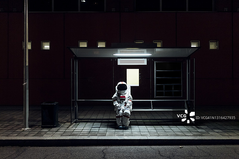 女宇航员晚上坐在公交车站图片素材