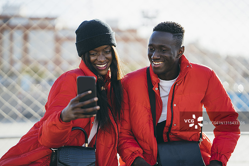 穿着红色夹克在户外用智能手机的幸福夫妇图片素材