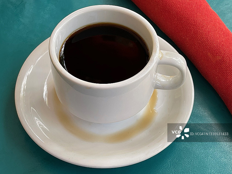 蓝色的桌子上放着一杯浓咖啡和红餐巾图片素材