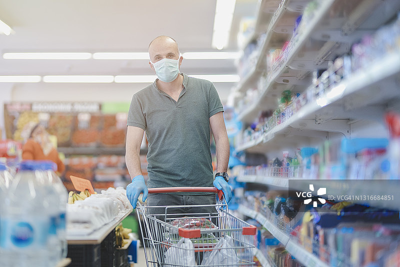 一个戴着面具和橡胶手套的男人在超市里图片素材