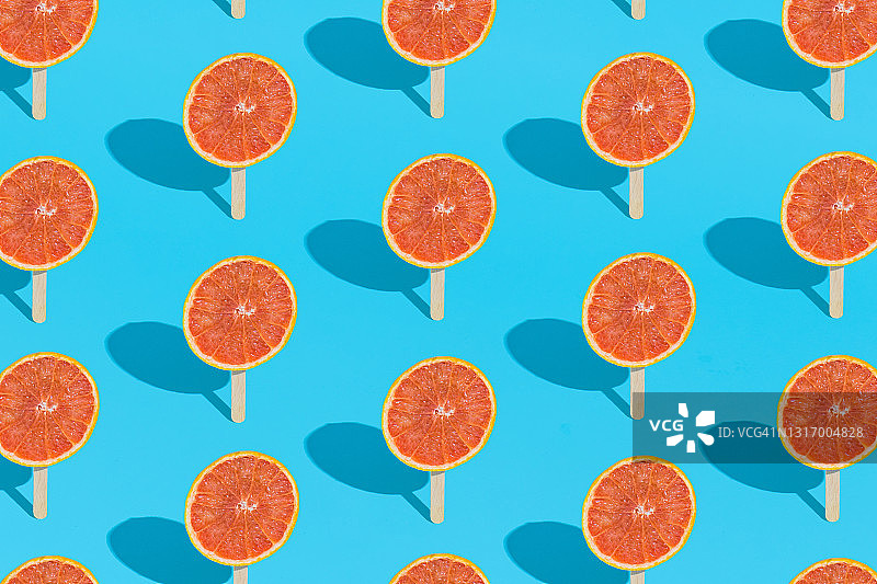 创意的夏季图案背景与红葡萄柚和冰淇淋棒在浅蓝色的背景。有机热带果汁。最小的夏季食物。图片素材