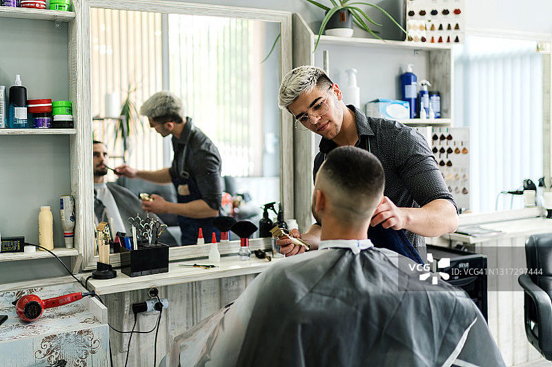 一名男子正在理发店里接受男理发师的理发图片素材