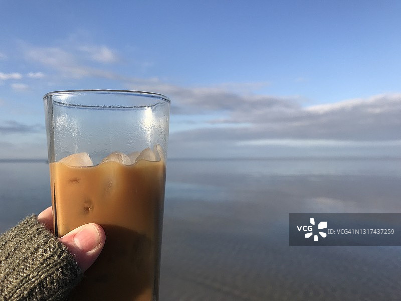 第一人称视角的一个女人拿着一杯冰咖啡在海滩沿着切萨皮克湾图片素材