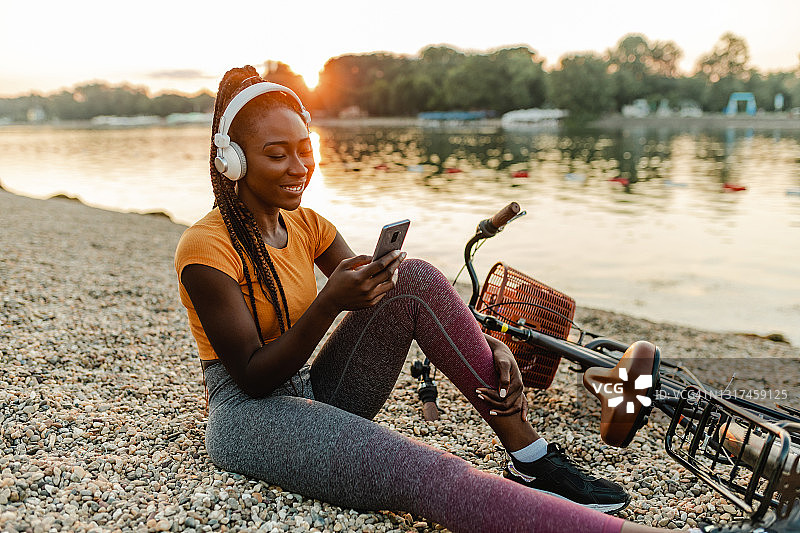 非裔美国妇女使用手机和休息骑自行车图片素材