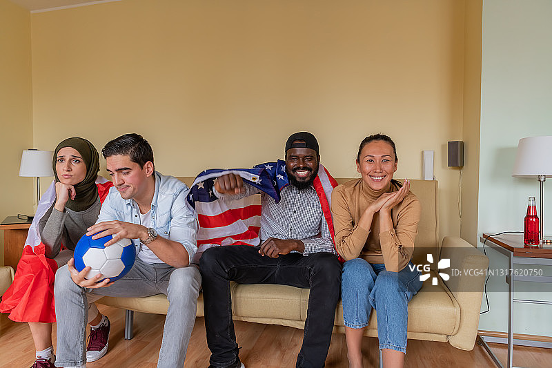 一群来自美国和加拿大的年轻朋友在现代公寓享受一场足球比赛。图片素材