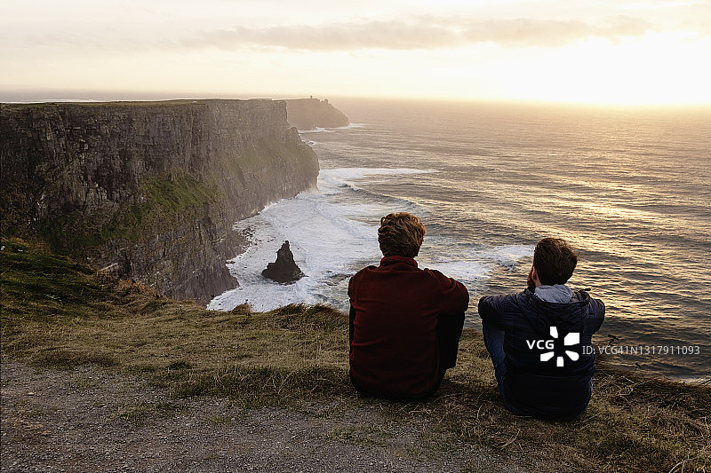 两名男子坐在爱尔兰克莱尔郡的莫赫悬崖上图片素材
