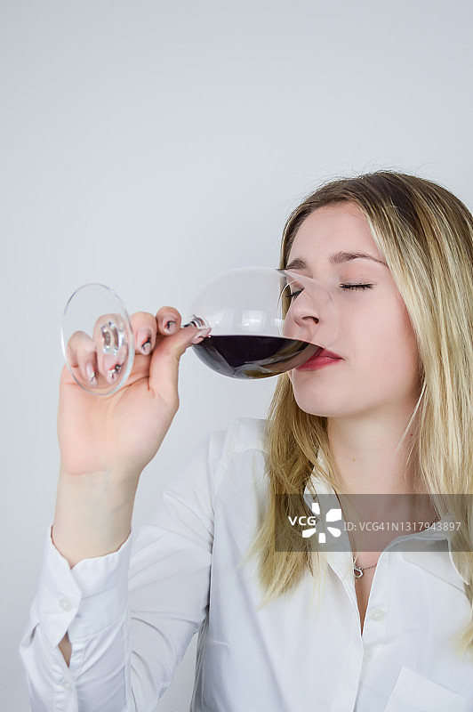 一个年轻漂亮的金发女人在品酒会上品尝一杯红酒图片素材
