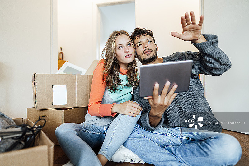 一对年轻夫妇坐在家里规划数字平板电脑图片素材