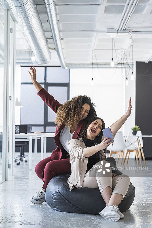 女企业家们举着手臂，在办公室的豆包上用智能手机自拍图片素材