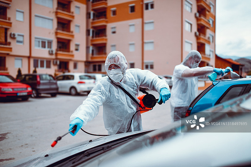 医护人员在公寓外为新冠肺炎感染社区的汽车消毒图片素材