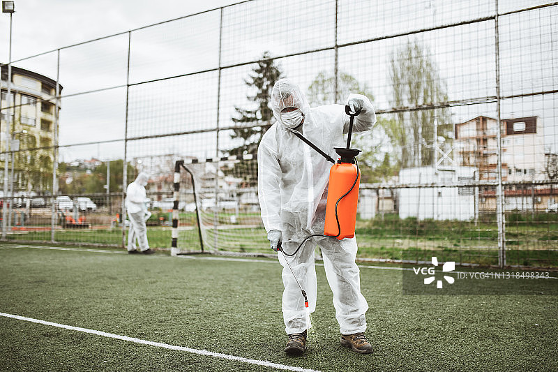 医务人员用消毒化学品喷洒足球场线和球门柱图片素材