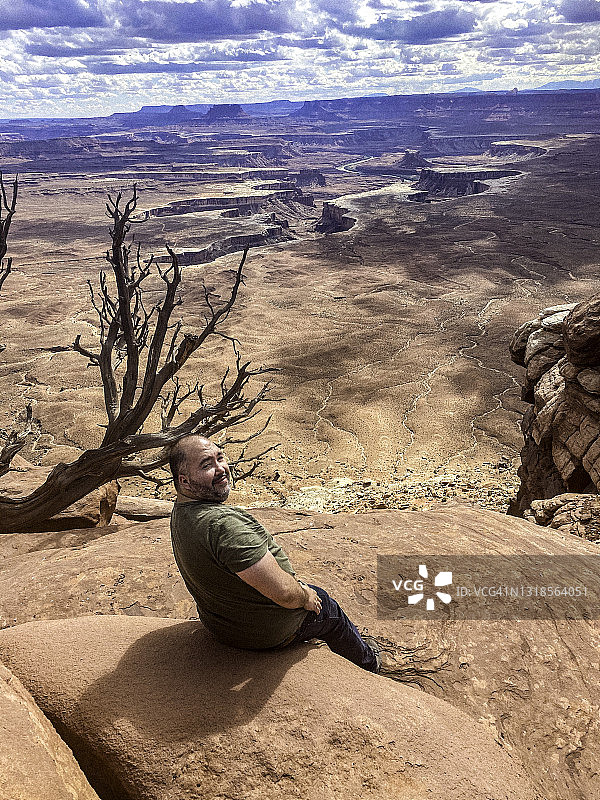 一个男人坐在峡谷地国家公园的峡谷边缘图片素材