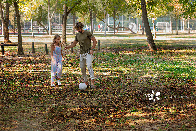快乐的爸爸和女儿在户外玩足球。图片素材